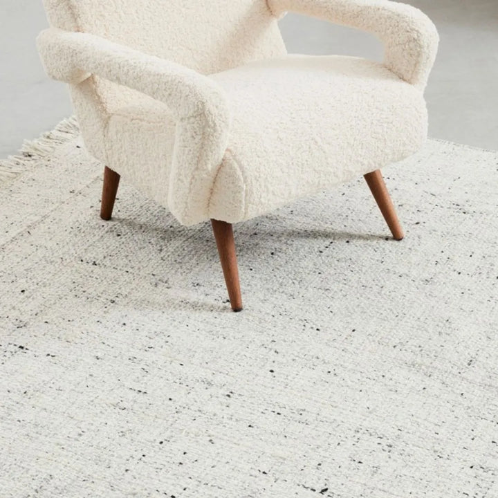 Tappeto naturale 200x300 cm con frange abbinato a una poltrona crema

