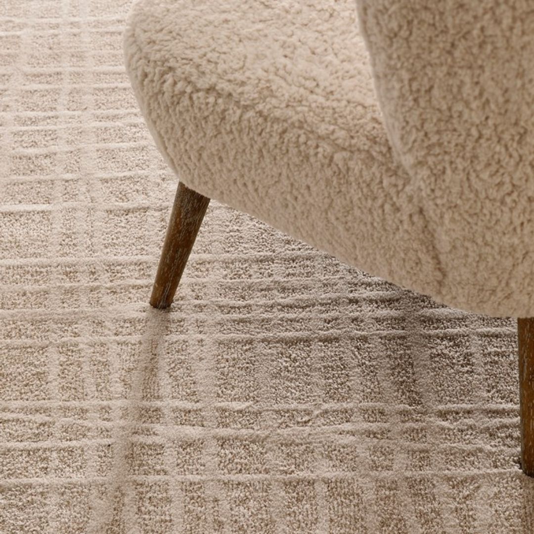Tappeto Tania beige cream in un ambiente moderno con poltrona in tessuto chiaro