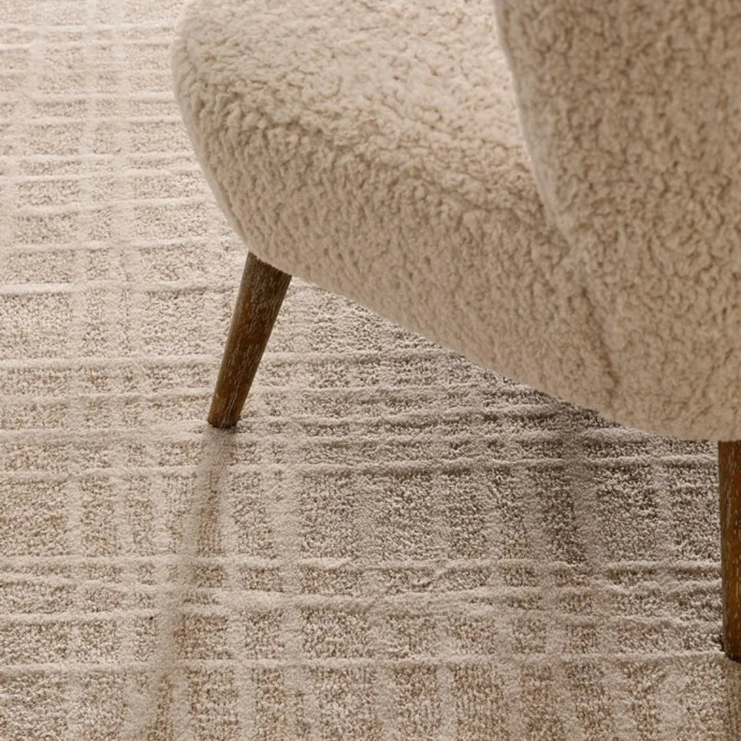 Tappeto Tania beige cream in un ambiente moderno con poltrona in tessuto chiaro