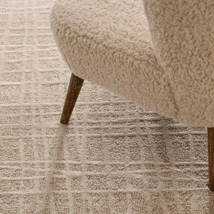 Tappeto Tania beige cream in un ambiente moderno con poltrona in tessuto chiaro