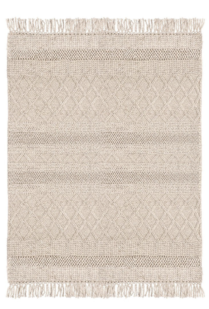 Vista dall’alto di un tappeto intrecciato beige con motivi a rombi e frange, ideale per arredamenti naturali e minimalisti