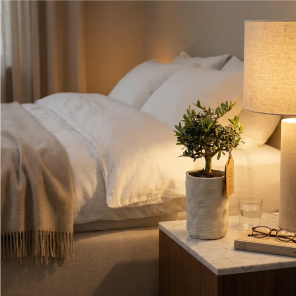 Sul comodino in marmo con lampada lino, bicchiere d'acqua e occhiali, luce intima serale