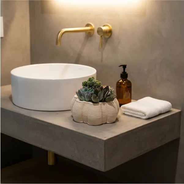 Piante grasse e cactus in vaso Itis in ceramica artigianale su mobile bagno in microcemento, soluzione decorativa per bagno contemporaneo.