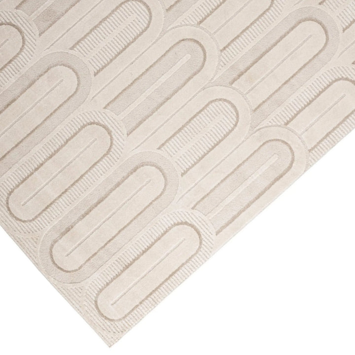 Particolare del tappeto beige con texture a rilievo e pattern ad archi simmetrici.