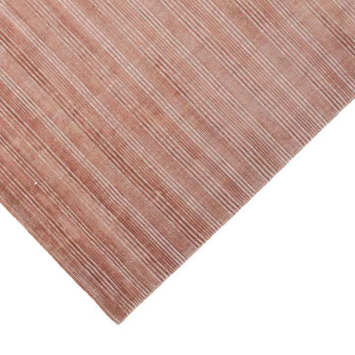 Dettaglio del tappeto effetto bouclé a righe color terracotta, con trama in rilievo e texture fitta.