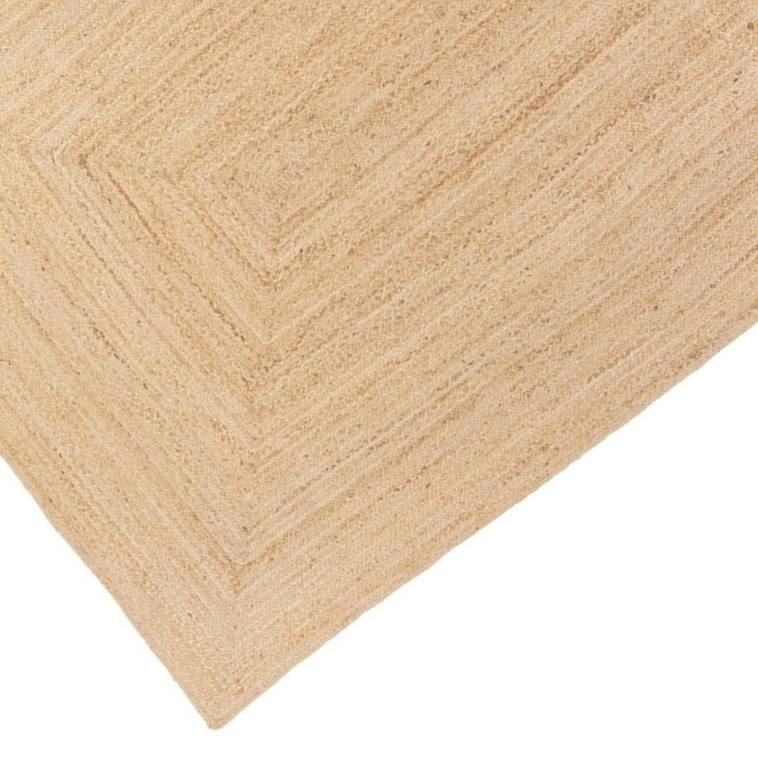 Dettaglio dell'angolo del tappeto in juta intrecciata, con motivo geometrico a trama rettangolare.