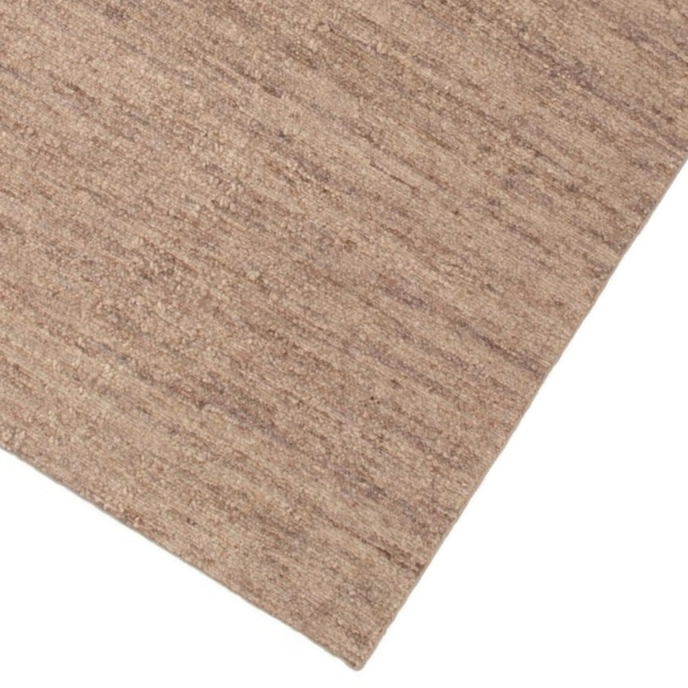 Dettaglio angolare del tappeto naturale beige che evidenzia la trama intrecciata in fibra di juta lavorata a mano.

