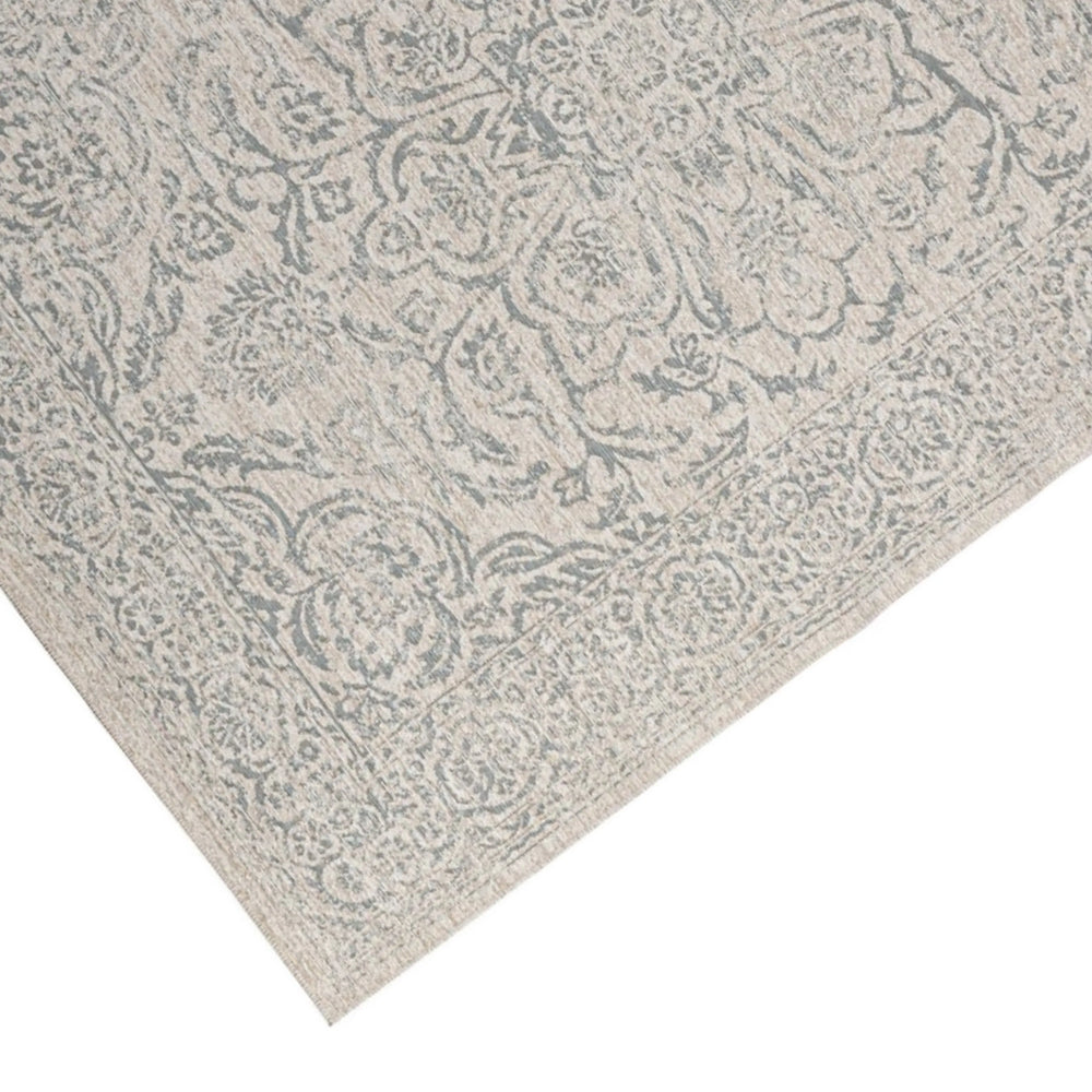 Dettaglio angolo tappeto decorativo orientale beige con motivo floreale classico e bordo lavorato.