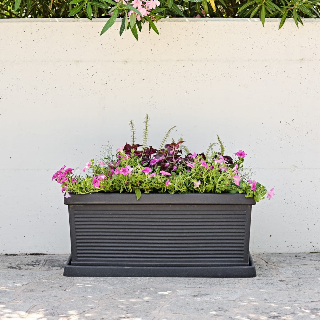 Fioriera rettangolare nera con superficie rigata e fiori rosa e viola in stile urbano