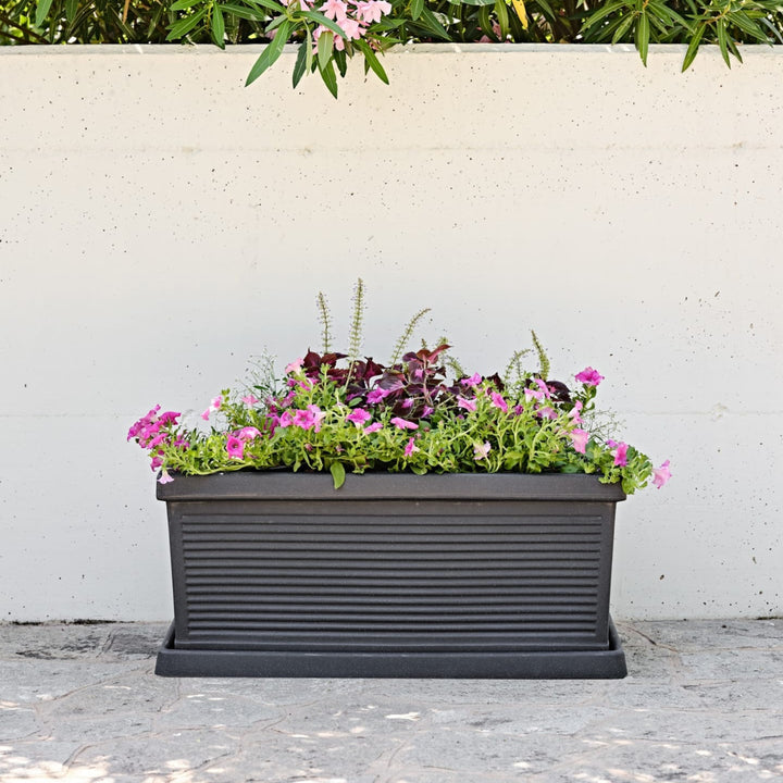 Fioriera rettangolare nera con superficie rigata e fiori rosa e viola in stile urbano