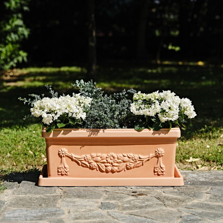 Fioriera in terracotta decorata con ortensie bianche ed eucalipto su vialetto in pietra