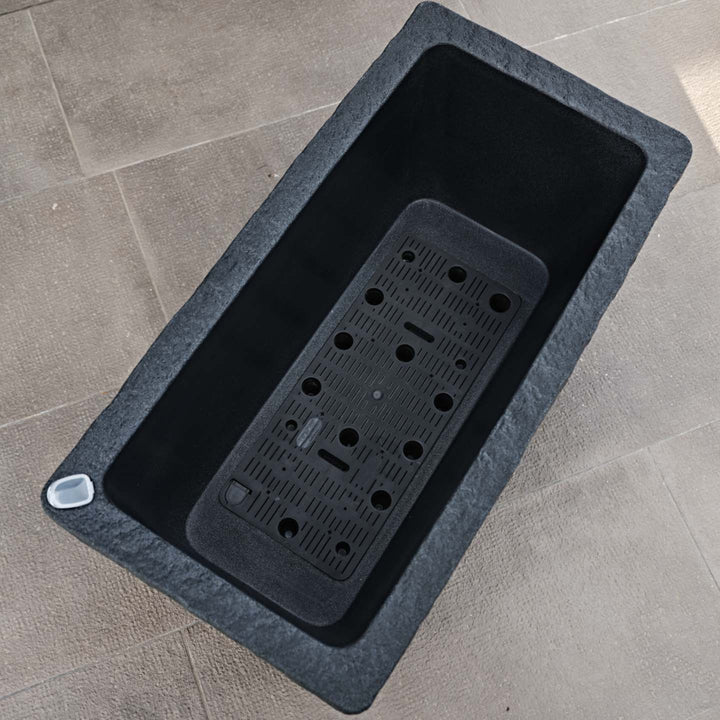 Dettaglio interno vaso rettangolare effetto pietra con griglia di drenaggio e sistema di riserva d’acqua integrato

