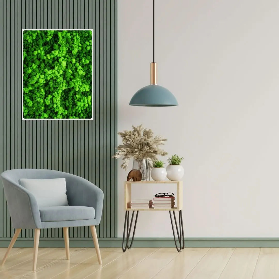 Quadro rettangolare in muschio stabilizzato con cornice bianca su parete verde, accanto a poltrona moderna e mobile in legno – I Giardini di Giulia