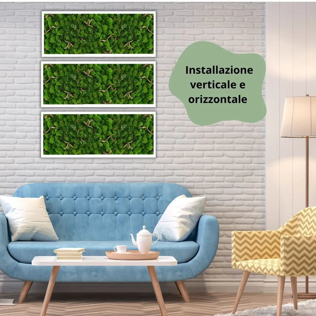 Tris di quadri rettangolari in muschio stabilizzato con cornice bianca e inserti in legno naturale, installati orizzontalmente su parete con mattoni bianchi sopra un divano azzurro, in ambiente moderno con lampada e poltrona gialla.