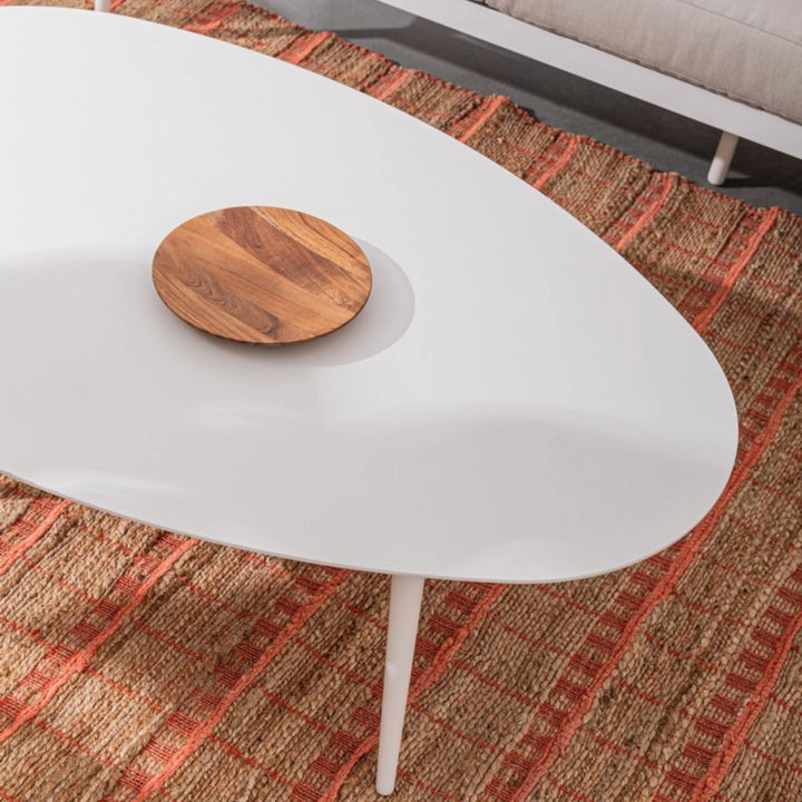 Dettaglio di tappeto in juta intrecciata con pattern a quadri in terracotta, abbinato a tavolino bianco moderno con vassoio in legno decorativo.