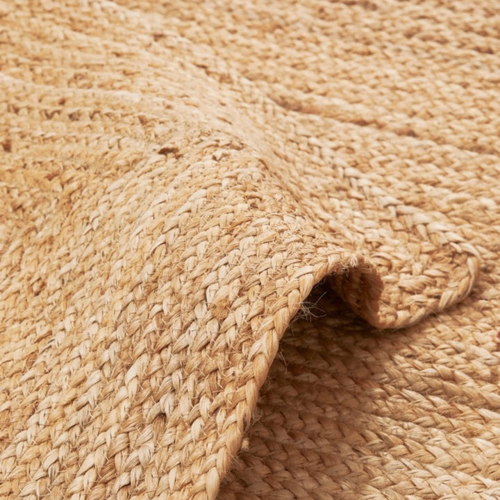 Dettaglio del tessuto intrecciato di un tappeto in juta naturale, con trama robusta e finitura rustica.