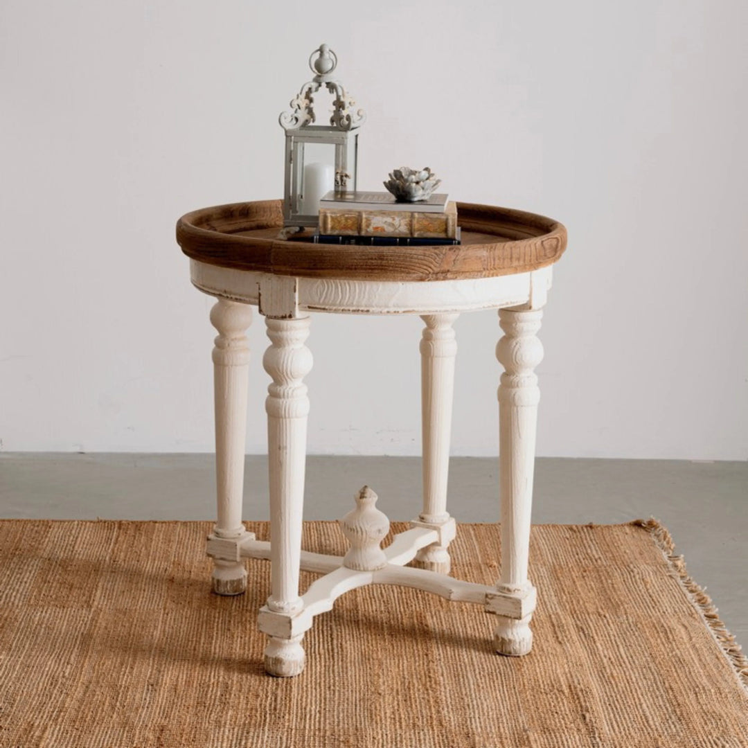 Tappeto in juta naturale con frange, ambientato con tavolino vintage in legno bianco e decorazioni d’arredo.