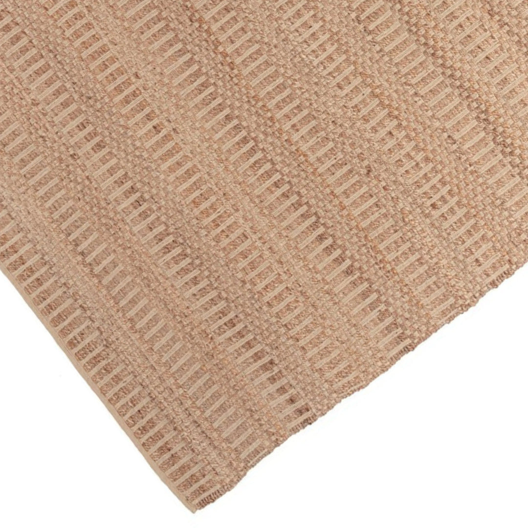 Dettaglio angolare del tappeto in juta con righe rosa tono su tono e tessitura artigianale.