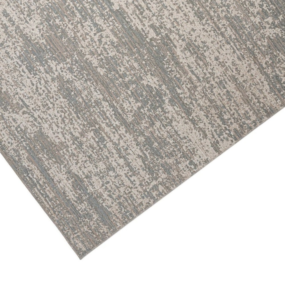 Dettaglio angolare di un tappeto moderno con finitura materica in beige e blu, effetto sfumato e texture a rilievo.

