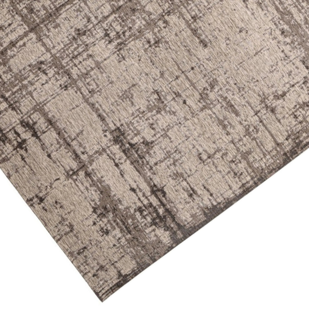 Dettaglio dell'angolo del tappeto moderno beige e marrone con motivo vissuto, tessitura a rilievo e finiture curate.