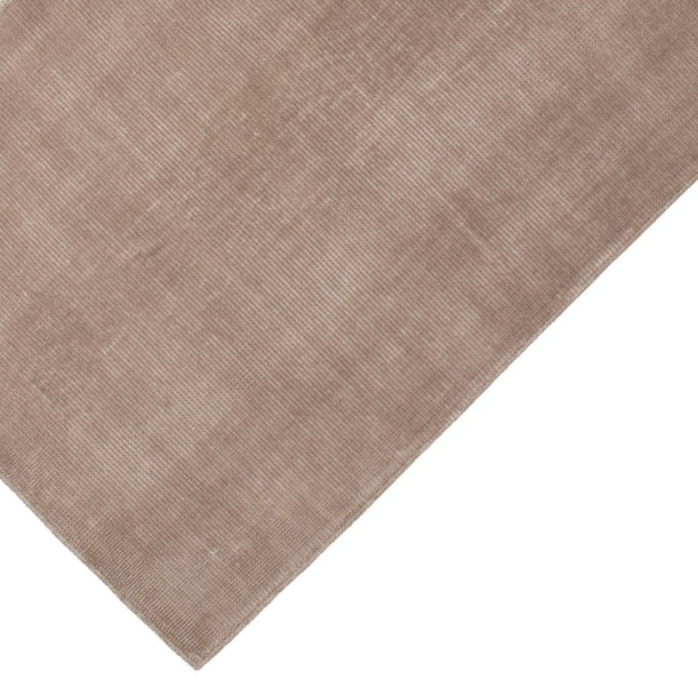 Dettaglio angolo tappeto tinta corda con finitura vellutata e lavorazione bouclé, perfetto per ambienti neutri e moderni