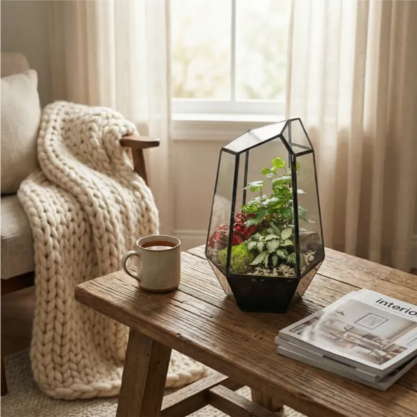 Terrarium su tavolino legno rustico in soggiorno hygge con coperta maglia, tazza tè, atmosfera accogliente