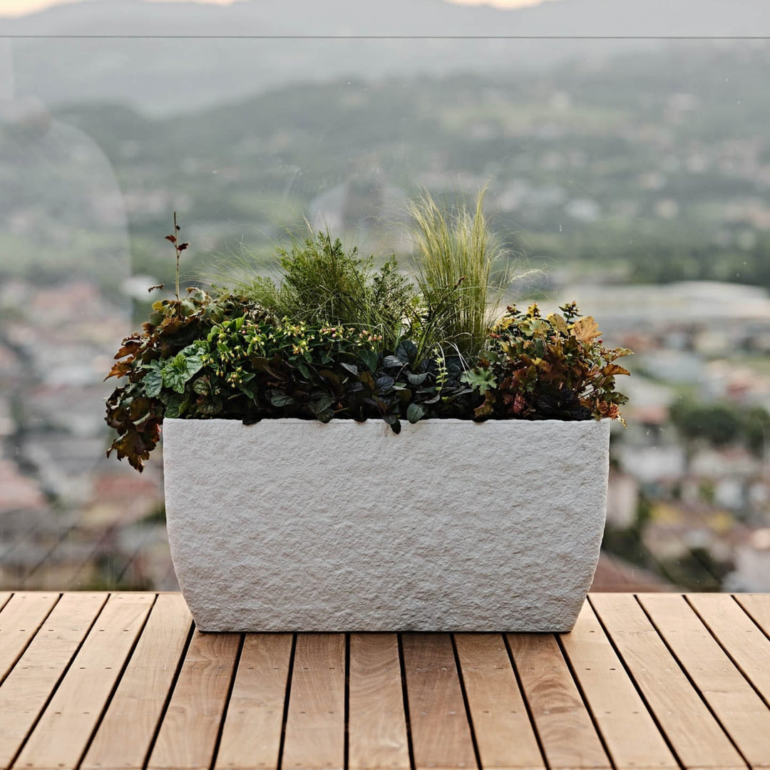 Vaso effetto pietra bianco con composizione di piante da esterno su terrazzo panoramico in legno