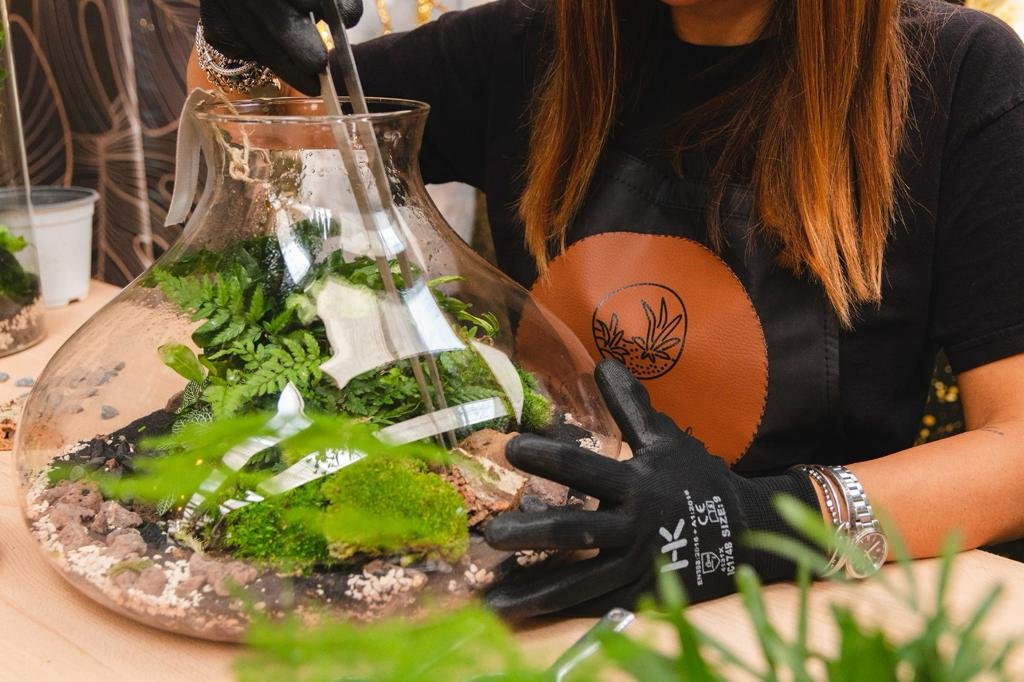 Immagine mostra una ragazza intenta alla realizzazione di un terrarium di piante